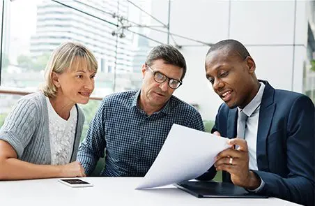 Three people are looking at a paper.