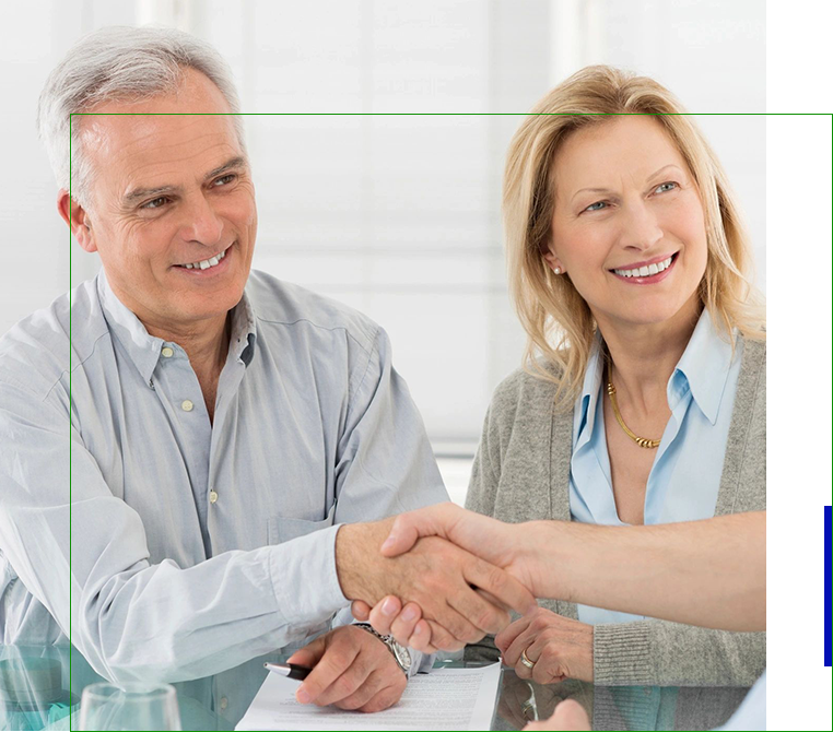 A man and woman shaking hands over a table.